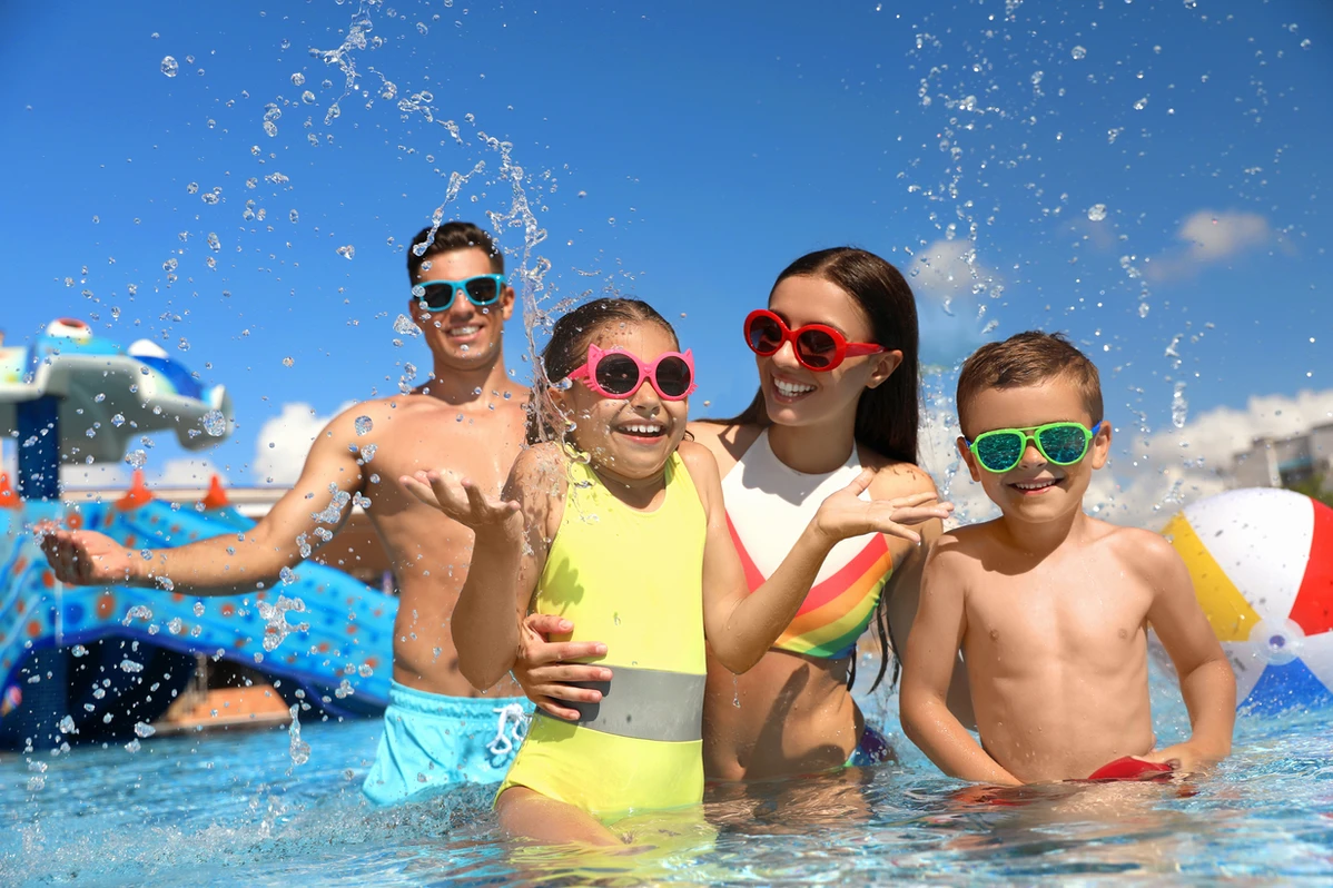 four people standing in pool with sunglasses and smiles